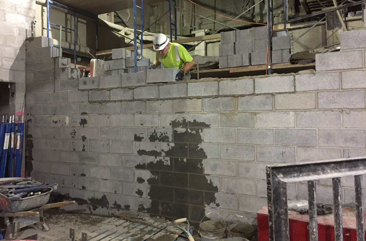 Een metselaar zet een muur in betonblokken op